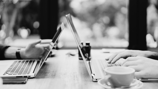 Two laptops with people working opposite of each other on their social media marketing strategy