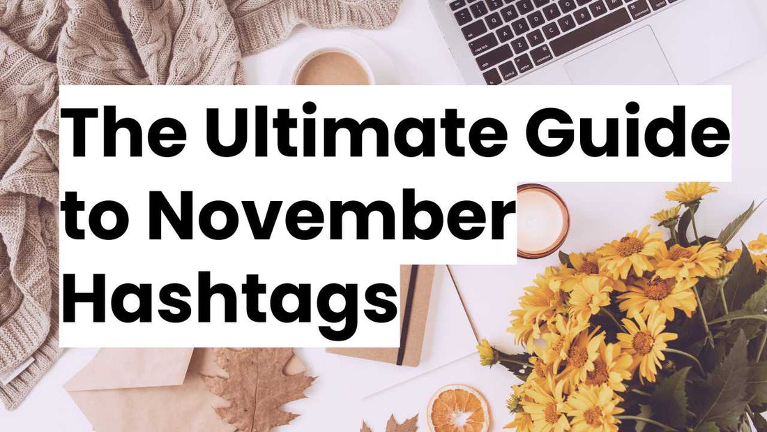 Flat lay of cozy autumn items, including a laptop, a warm knitted blanket, coffee, sunflowers, and a candle on a white surface, with the text 'The Ultimate Guide to November Hashtags' overlayed in bold.