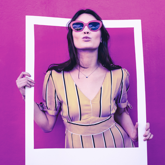 Woman in striped dress posing with oversized sunglasses, holding a white frame of VIP Services - Platinum against a purple background, perfect for social media marketing content by Socially Inclined.